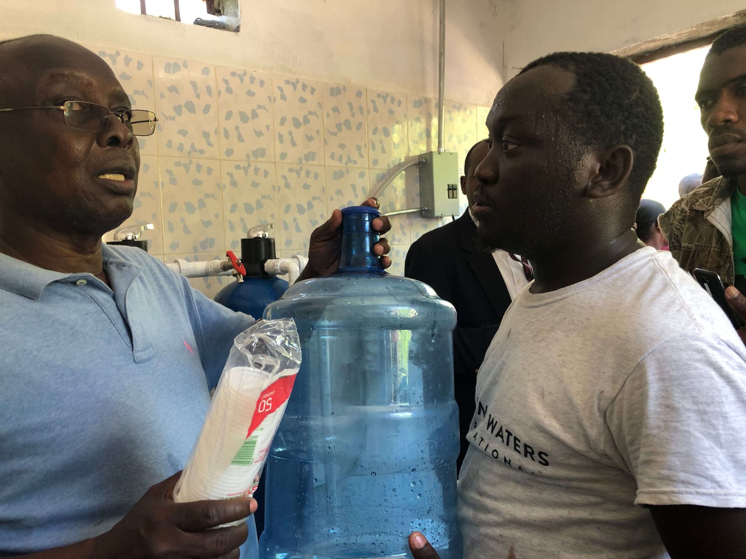 Men holding a jug of water and cups
